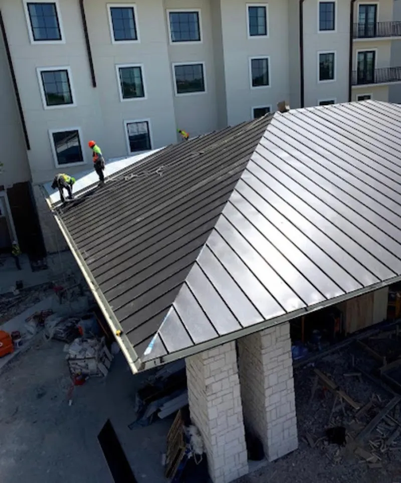 Crew installing standing seam metal roof panels on a commercial project in Glenn Dale